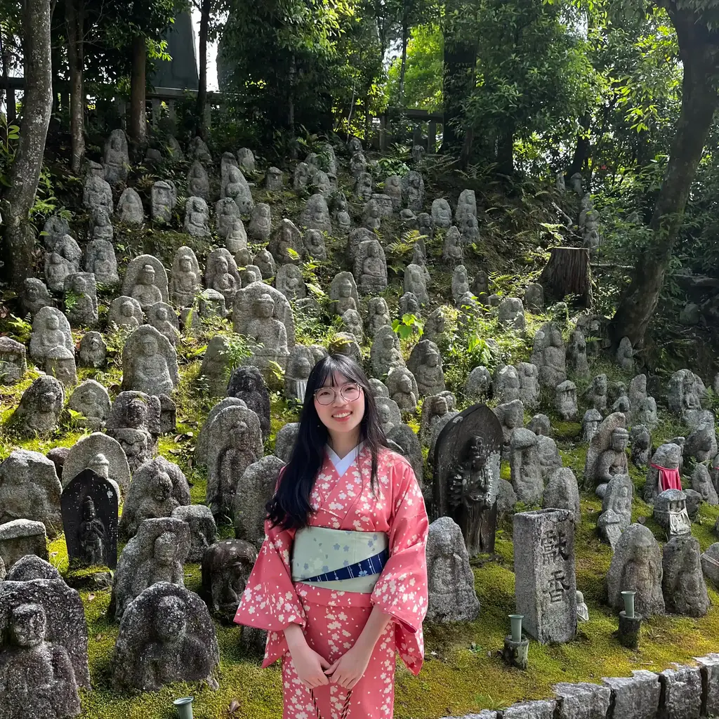 Photo of Victoria in kimono smiling in front of a forest of buddha statues